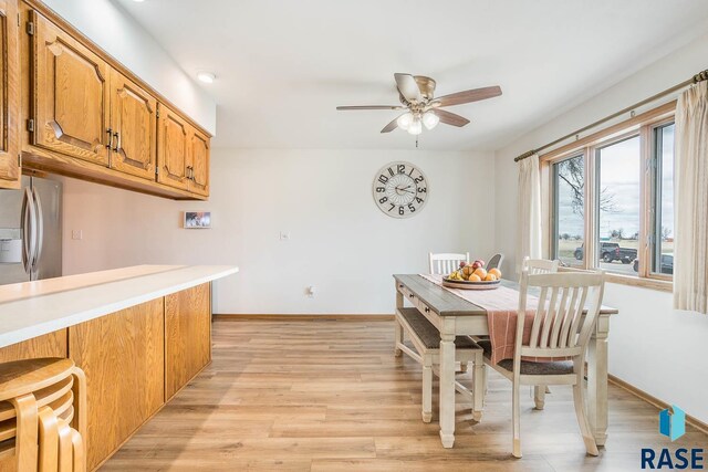 dining room featuring baseboards, light wood finished floors, and ceiling fan