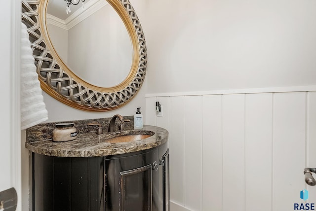 bathroom featuring wainscoting, crown molding, and vanity