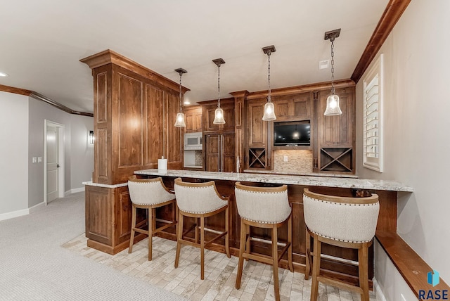bar with decorative backsplash, baseboards, ornamental molding, pendant lighting, and built in appliances