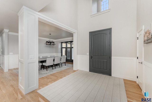 entrance foyer featuring light wood finished floors, a wainscoted wall, and a chandelier
