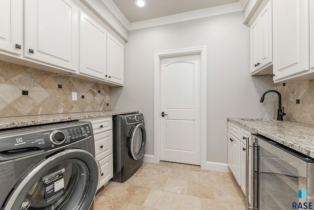 laundry area featuring baseboards, wine cooler, a sink, cabinet space, and separate washer and dryer