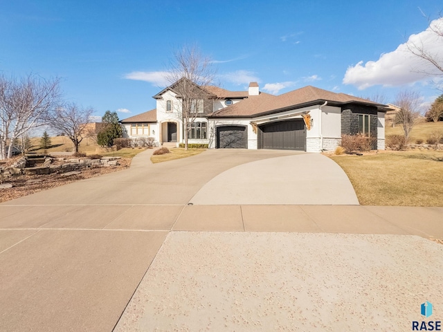 view of front of property featuring concrete driveway, stone siding, a front yard, a garage, and a chimney