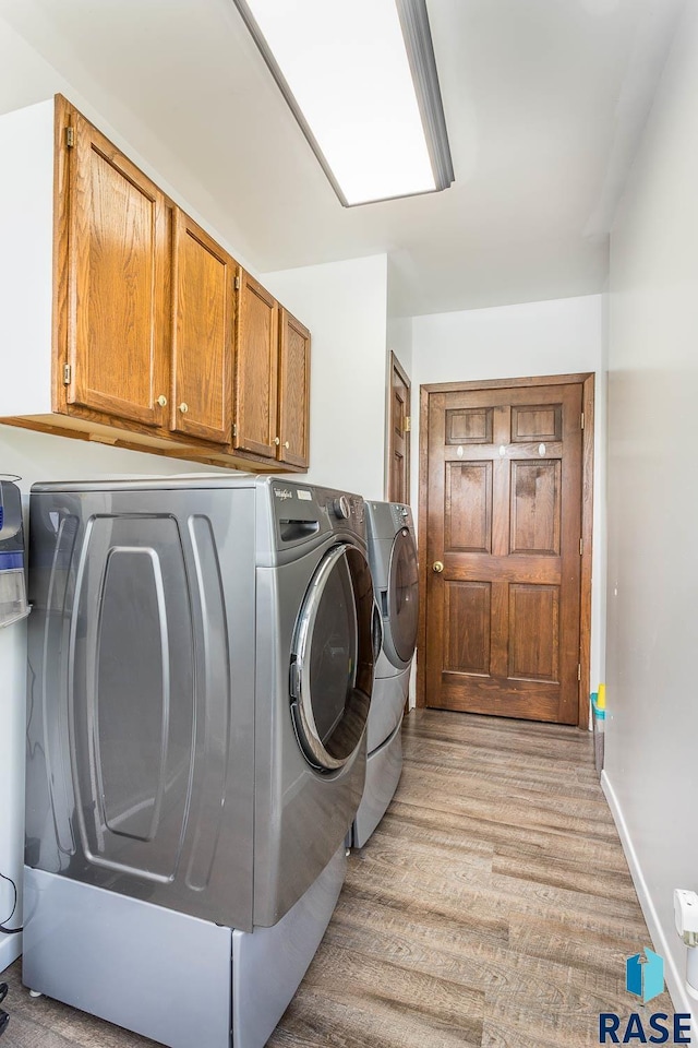 1220 NE 3rd St, Madison, SD 57042 - clothes washing area featuring light wood finished floors, cabinet space, baseboards, and separate washer and dryer