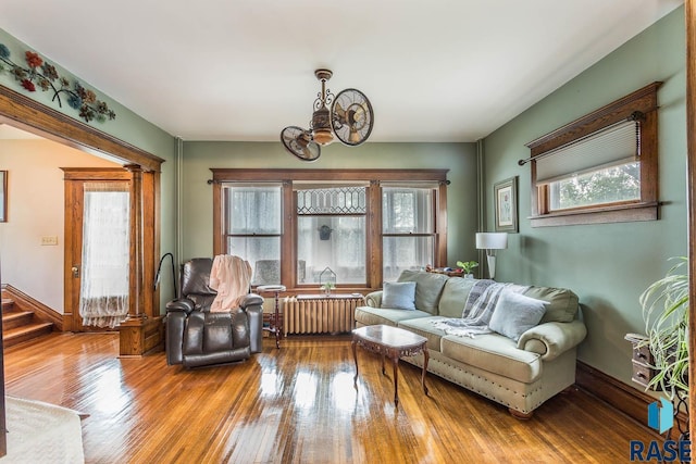 1220 NE 3rd St, Madison, SD 57042 - living room featuring radiator heating unit, hardwood / wood-style flooring, an inviting chandelier, and stairs