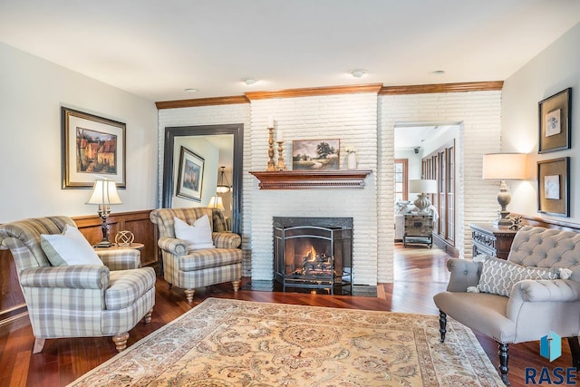 living room featuring a fireplace, wood finished floors, and brick wall