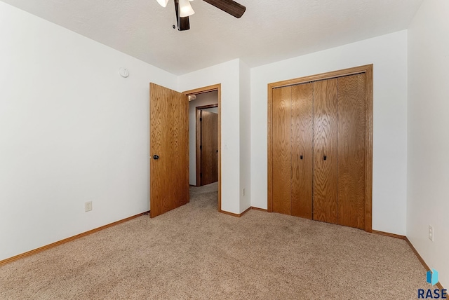 unfurnished bedroom with baseboards, a textured ceiling, carpet floors, ceiling fan, and a closet