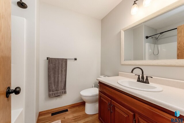 bathroom with visible vents, a shower, toilet, wood finished floors, and vanity