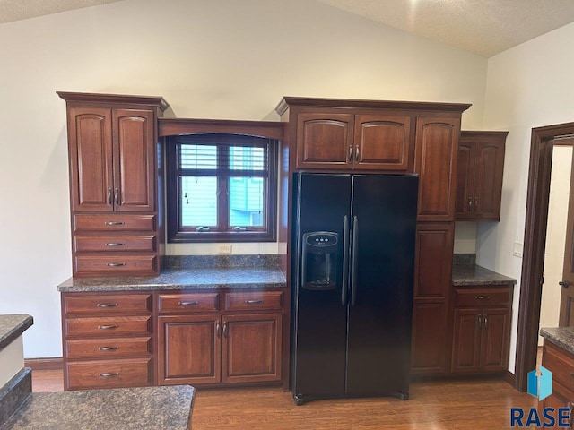 kitchen with lofted ceiling, wood finished floors, and black fridge