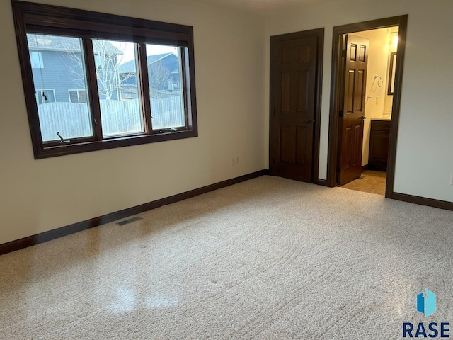 unfurnished bedroom featuring baseboards, connected bathroom, and visible vents