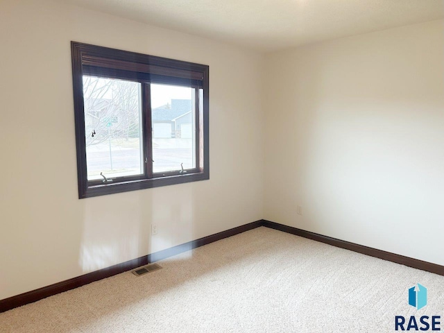 unfurnished room featuring baseboards, light colored carpet, and visible vents