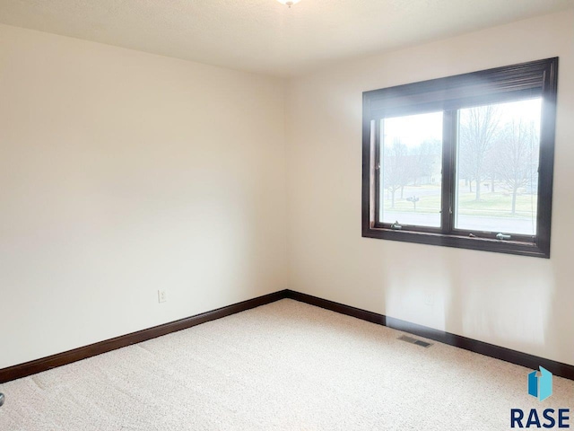 empty room featuring baseboards, visible vents, and carpet