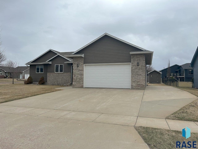 view of front of home with brick siding, driveway, a garage, and fence
