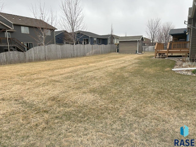 view of yard featuring an outdoor structure, a storage unit, fence, and a wooden deck