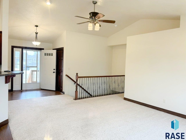 interior space featuring a ceiling fan, dark colored carpet, lofted ceiling, and visible vents