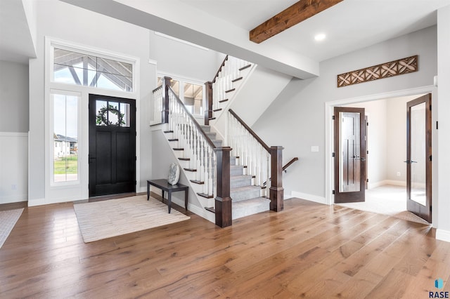 entrance foyer with stairs, recessed lighting, baseboards, beamed ceiling, and light wood-style flooring