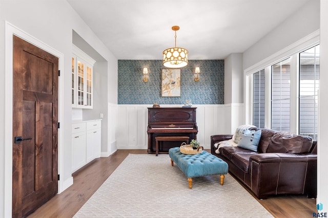 sitting room featuring wainscoting, wallpapered walls, and dark wood-type flooring