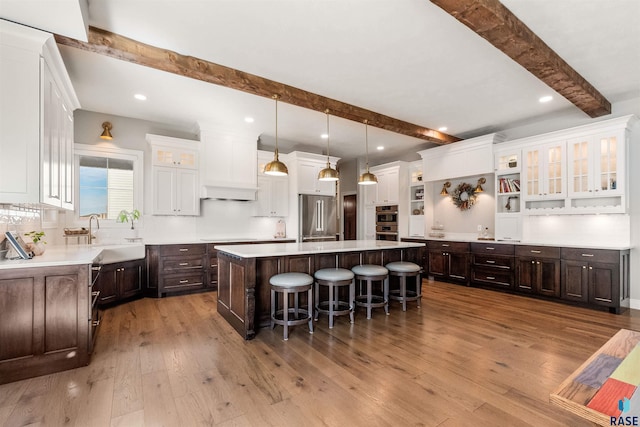 kitchen featuring dark brown cabinetry, a sink, a kitchen island, a kitchen breakfast bar, and appliances with stainless steel finishes