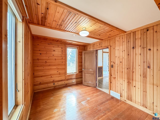unfurnished bedroom with hardwood / wood-style floors, visible vents, and wooden walls
