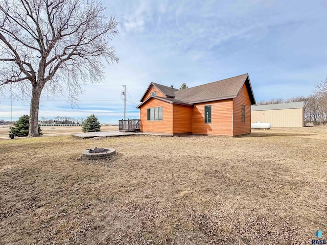 view of home's exterior with a fire pit and roof with shingles