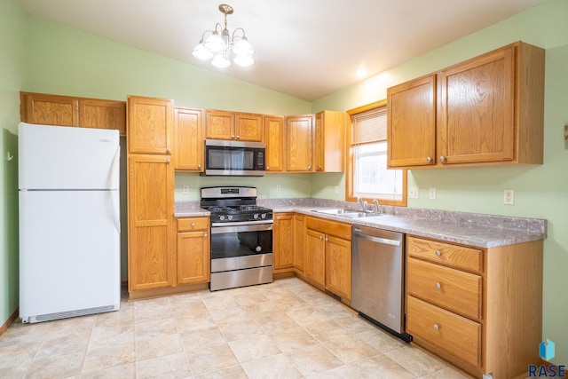 kitchen with a notable chandelier, light countertops, a sink, appliances with stainless steel finishes, and lofted ceiling