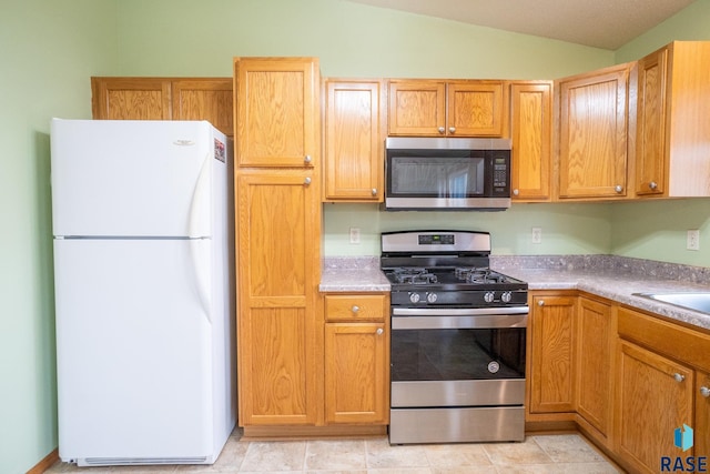 kitchen with light countertops, appliances with stainless steel finishes, and vaulted ceiling