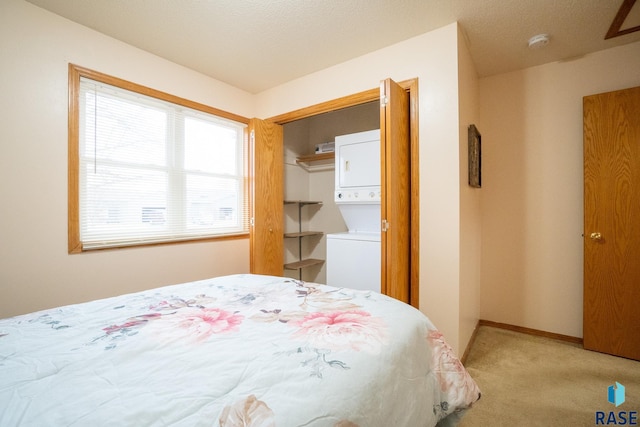 bedroom with stacked washer / dryer, light carpet, and baseboards