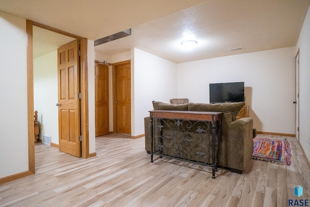 living area featuring baseboards, visible vents, and light wood-style flooring