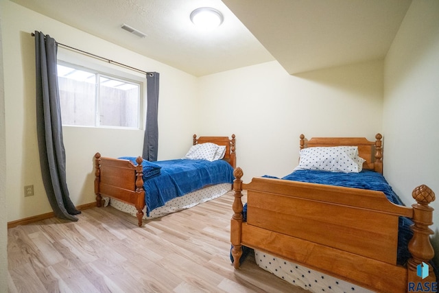 bedroom featuring baseboards, visible vents, and wood finished floors