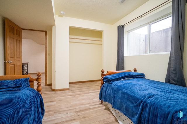 bedroom featuring baseboards, a closet, and light wood-type flooring