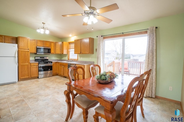 dining room with ceiling fan with notable chandelier, lofted ceiling, and baseboards