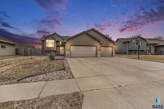 tri-level home featuring concrete driveway, a garage, and fence