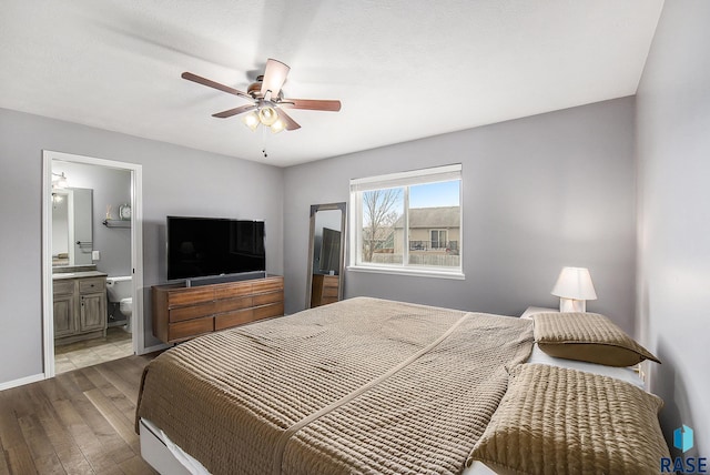 bedroom with baseboards, wood finished floors, ceiling fan, and ensuite bathroom