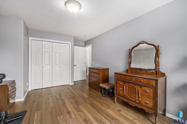 bedroom with baseboards, a closet, and wood finished floors