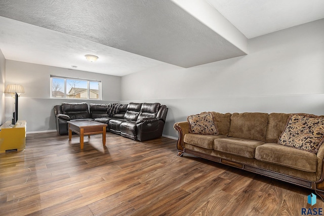 living room featuring a textured ceiling, baseboards, and wood finished floors