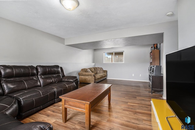 living room with baseboards, a textured ceiling, and wood finished floors