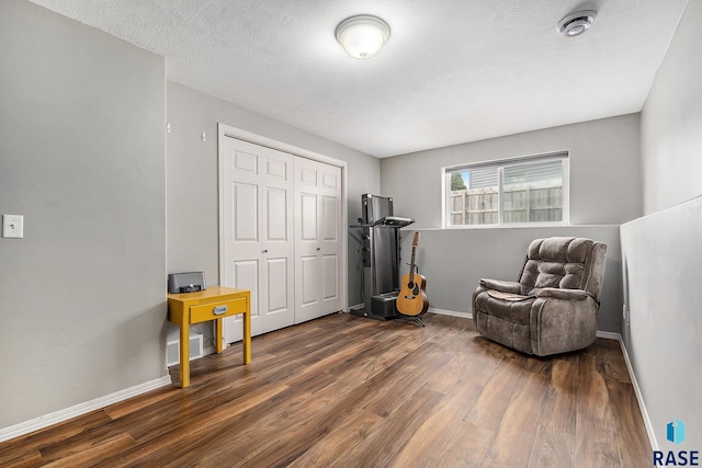 living area featuring dark wood-style floors, visible vents, baseboards, and a textured ceiling