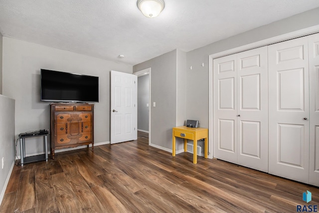 bedroom featuring a closet, baseboards, a textured ceiling, and wood finished floors