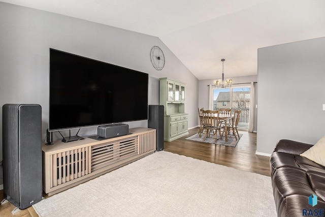 living room with baseboards, lofted ceiling, wood finished floors, and an inviting chandelier