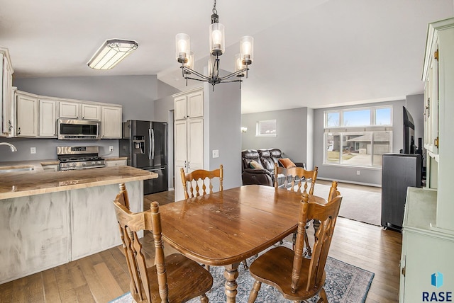 dining area featuring lofted ceiling, an inviting chandelier, and hardwood / wood-style flooring