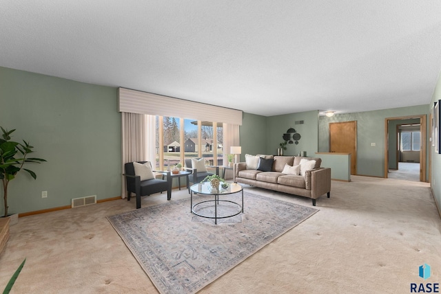 living room with baseboards, a textured ceiling, visible vents, and carpet