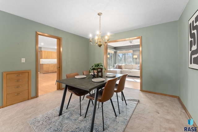 dining area with baseboards, ceiling fan with notable chandelier, and light carpet