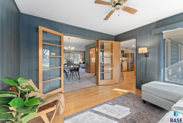 living area with ceiling fan with notable chandelier and hardwood / wood-style floors
