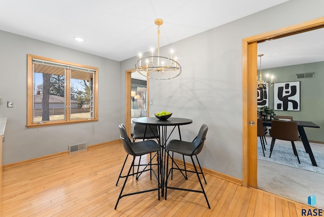 dining space with visible vents, a chandelier, and wood-type flooring