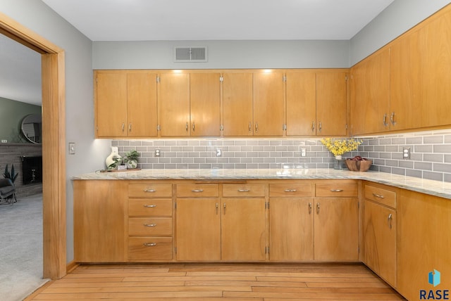 kitchen with backsplash, light wood-style flooring, and visible vents