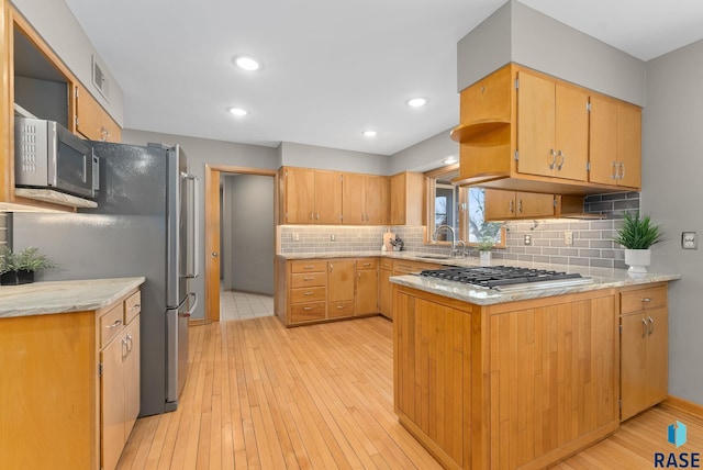 kitchen featuring a sink, stainless steel appliances, light wood finished floors, and visible vents