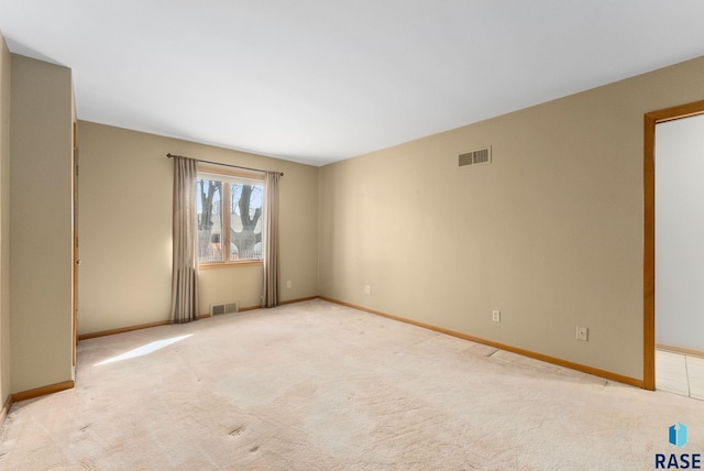 spare room featuring light carpet, baseboards, and visible vents