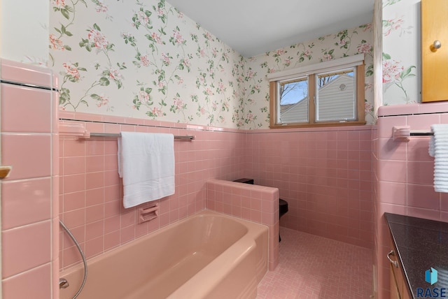 bathroom featuring a wainscoted wall, wallpapered walls, tile walls, and a garden tub