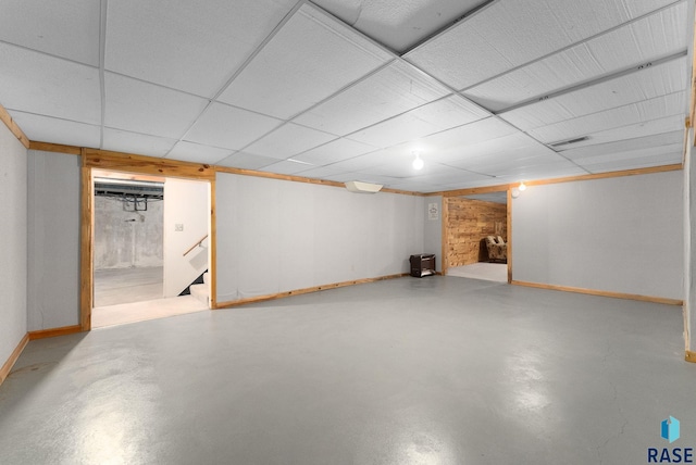 finished basement with a drop ceiling, baseboards, stairs, and visible vents