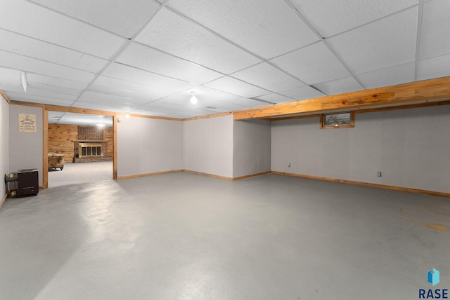 finished below grade area with baseboards, a fireplace, and a paneled ceiling