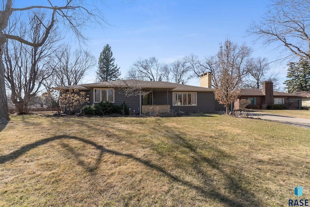 ranch-style house featuring a chimney and a front lawn